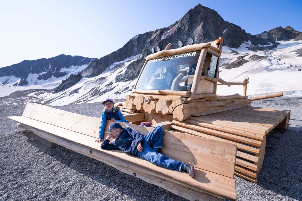 Kinder spielen auf der gro&szlig;en Holz-Pistenraupe am H&ouml;henspielplatz beim Stubaier Gletscher