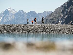 Family hiking on a gravel path against the mountain scenery of the Stubai Valley