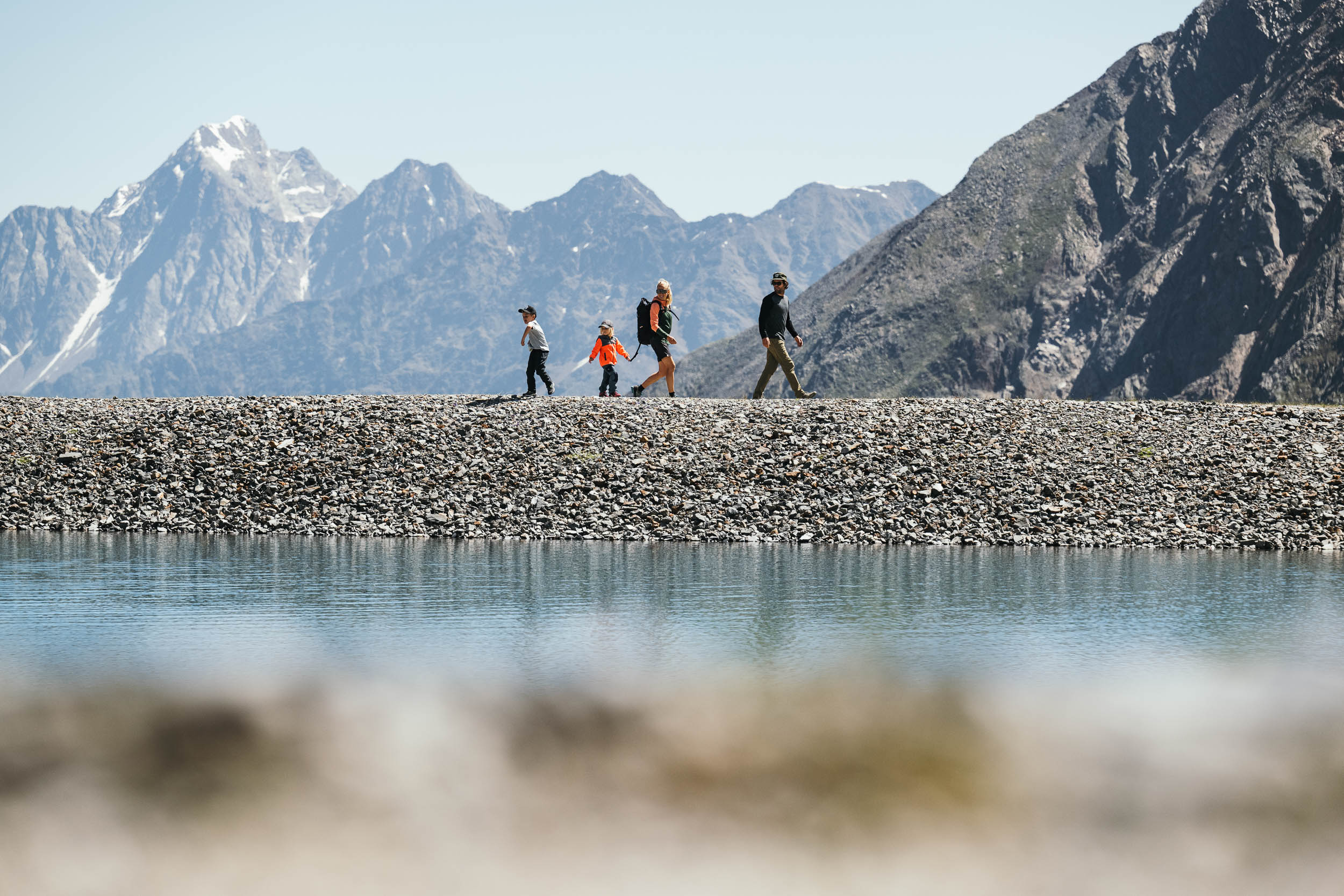 Familie wandert auf einem Kiesweg vor der Bergkulisse des Stubaitals